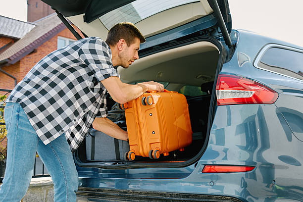 istock Man loading suitcase into car trunk, Packing luggage for travel 2215857214