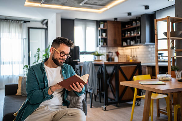 istock Young adult man enjoying a book in modern home 2215865191