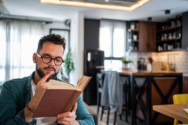 istock Focused young man reading a book in his modern apartment 2215865194
