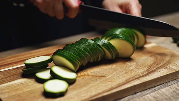 istock Female Chef Slicing Zucchini on Wooden Cutting Board. 2215867105