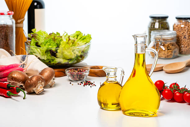 Two extra virgin olive oil bottles and vegetables salad on kitchen table