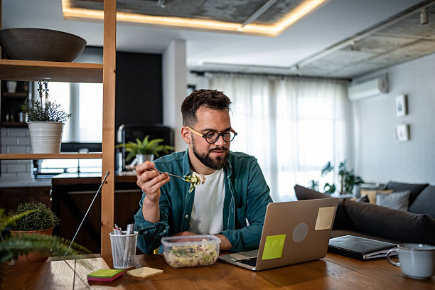 istock Young man eating salad and working from home office 2215871451