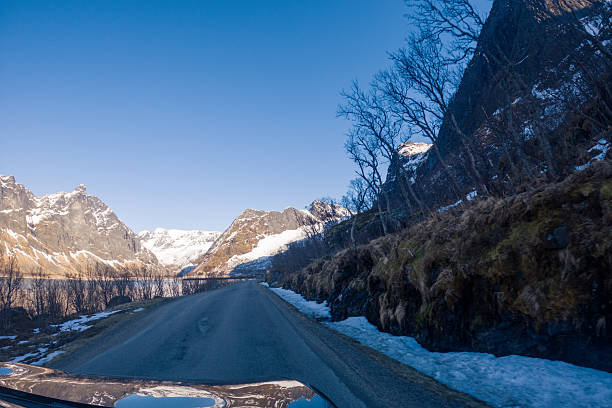 istock Scenic Mountain Road Alongside Serene Lake with Clear Blue Sky 2215872430