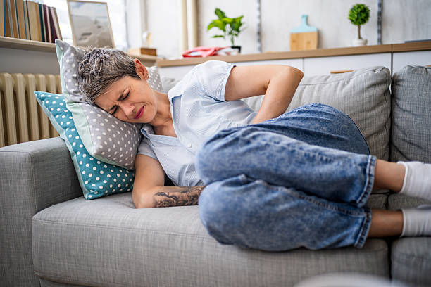 istock Mature woman suffering from abdominal pain while lying on sofa 2215872606