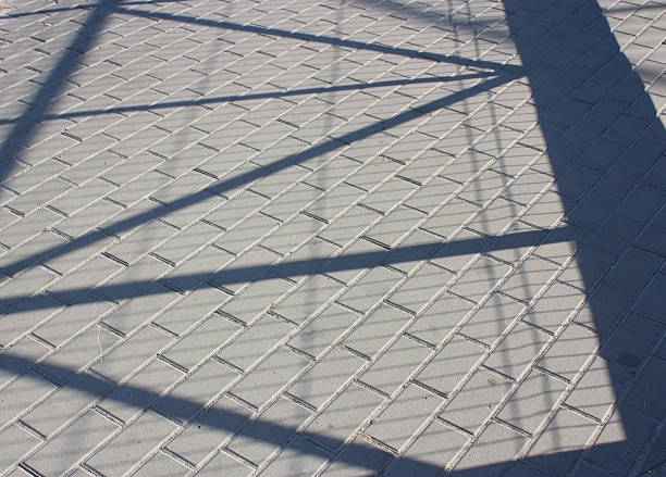 istock Sidewalk light grey rectangle tiles. Shadows from the fence 2215873511