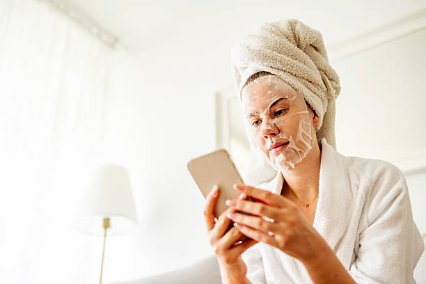 istock Woman Relaxing With Sheet Mask and Smartphone in Cozy Home Setting 2215878636
