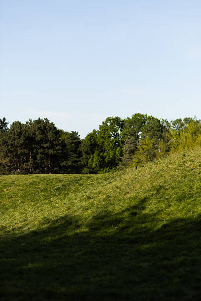 istock Hillside under a clear blue sky with green grass and trees 2215879578