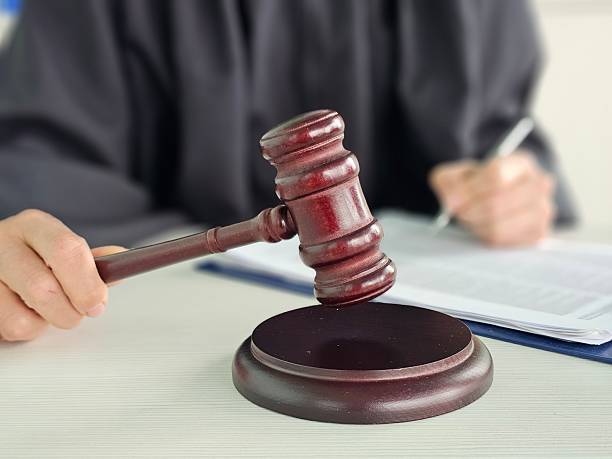 istock Judge presides over courtroom proceedings using gavel while reviewing case documents concept 2215882420