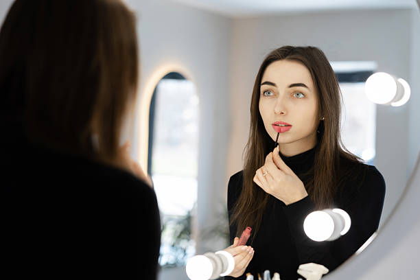 istock Woman Applying Lip Gloss While Looking in the Mirror 2215886499