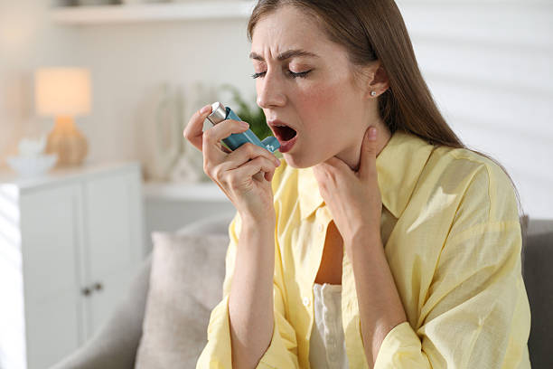 istock Young woman using asthma inhaler at home 2215887842