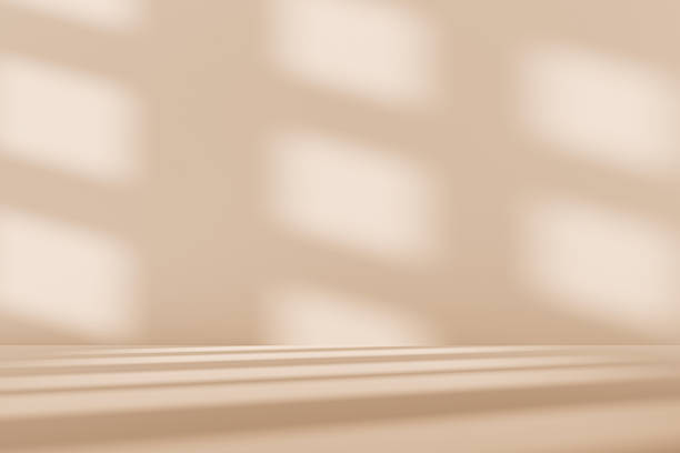 istock 3D beige studio room with a window shadow on the wall. Sunlight moves across the empty room. Brown background for product display, with space for text. 2215894243