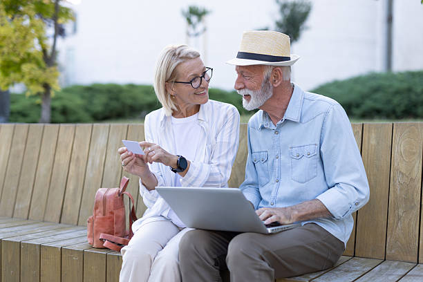 istock Senior man and woman using laptop and reading card on a bench. 2215894663
