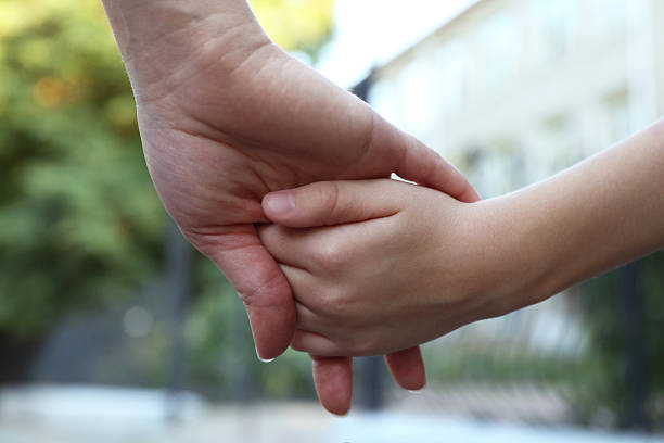 istock Mother and daughter holding hands outdoors, closeup 2215896857