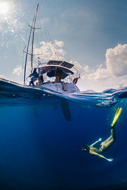 Beautiful woman relaxing and enjoying and playing underwater. near a sailboat.  She wears bikini and looks very attractive and graceful. Sunbeams coming from sea surface.