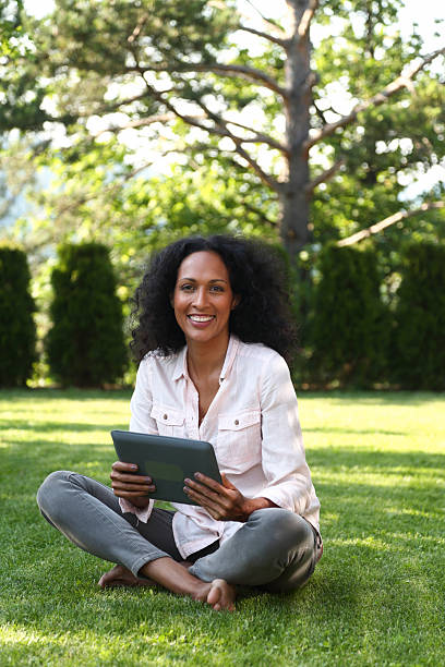 istock Smiling Woman Sitting on Grass Using Tablet 2215907755