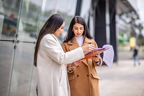istock Businesswomen collaborating outdoors while reviewing documents in a professional setting during daylight hours 2215912922