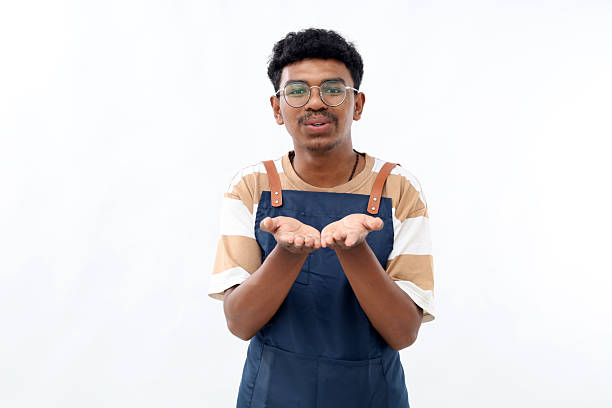 Young asian bartender man wearing apron showing his empty palm to the front, holding something isolated on white background