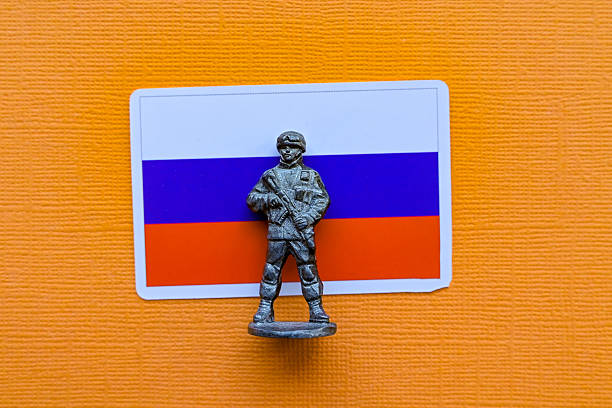 Concept of war, with little soldier toy running on battlefield of conflict with weapon in hands in selective focus with blurred soldier in background, placed on a military map. Macro shot.