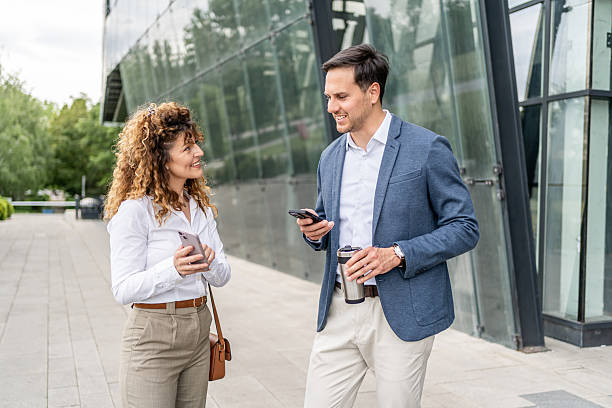 istock Businesspeople using smartphones and talking outside office building 2215918546
