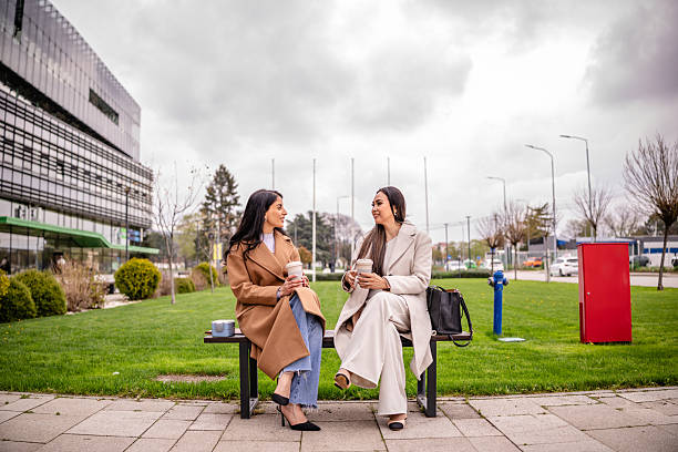 istock Two businesswomen enjoy a coffee break in a corporate garden setting while discussing business under a cloudy sky 2215919016