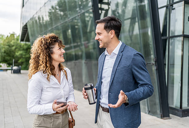 istock Businesspeople talking and smiling outdoors near office building 2215919736