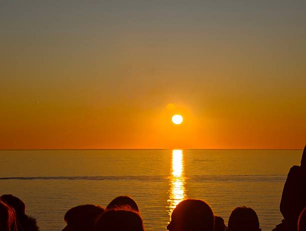 istock Silhouettes Watching a Golden Sunset Over Calm Sea 2215923320