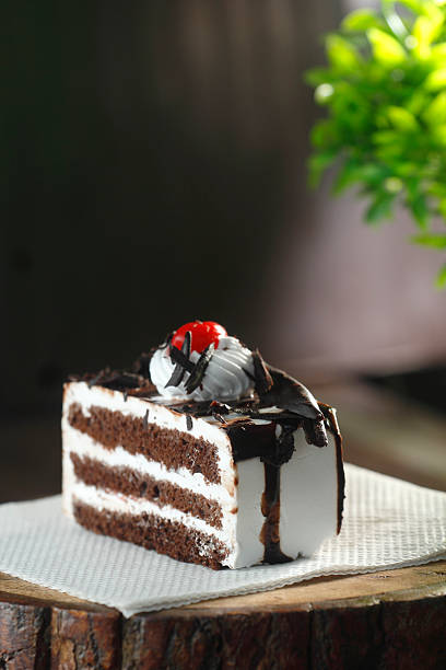 Close-up of a rich black forest pastry slice with whipped cream and cherry on top, styled on a rustic background. Perfect for dessert and bakery concepts.