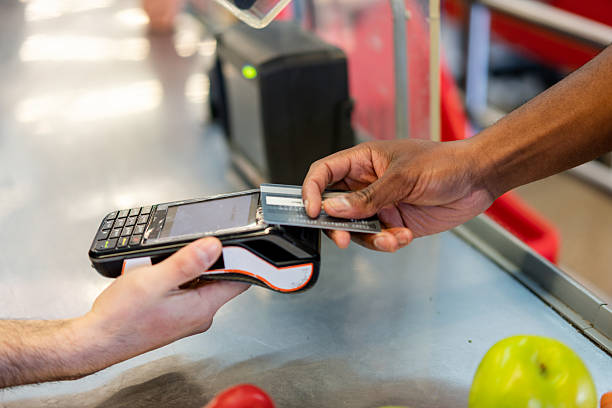 istock Supermarket cashier holding credit card machine while processing customer payment 2215927775