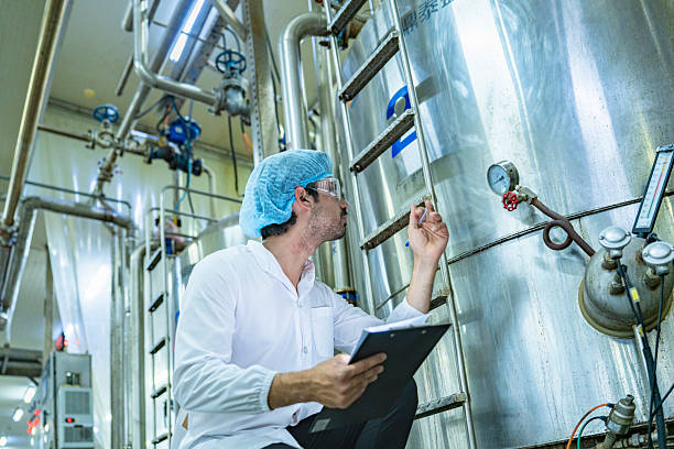 istock Worker examining an industrial tank and recording data on a clipboard, emphasizing the importance of safety, quality assurance, and technological advancement in industrial environments. 2215930592