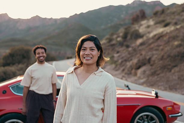 istock Couple smiling while leaning on the car during a road trip 2215930824