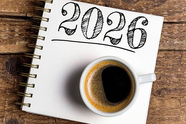 New year resolutions 2026 on desk. 2026 resolutions list with notebook, coffee cup on table. Goals, resolutions, plan, action, checklist concept. New Year 2026 template