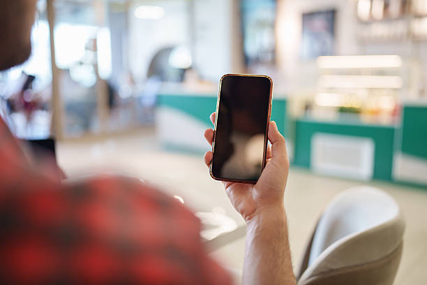 istock Over-the-Shoulder View of Man Holding Smartphone with Blank Screen 2215931323