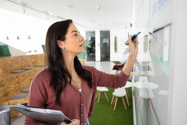istock Focused young businesswoman make marker notes on whiteboard wall 2215931420