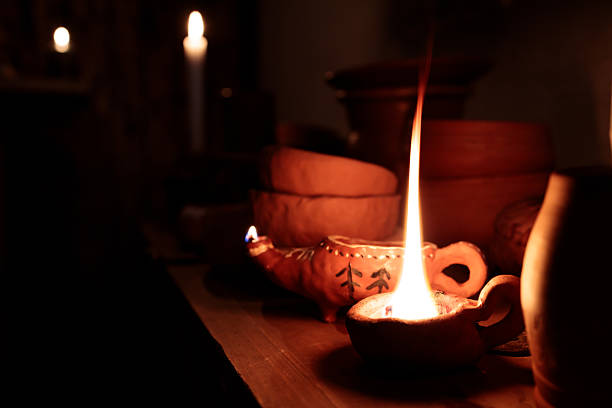 A table with a lit candle and other items on it. The candle is the main focus of the image, and it creates a warm and cozy atmosphere. The other items on the table, such as bowls and vases