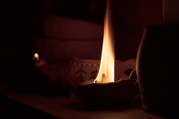 A candle is lit in a small holder. The holder is on a table