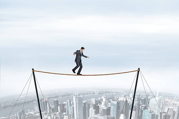 istock Man Balancing On A Tightrope Above Big City 2215934304