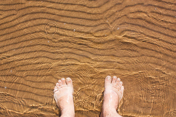 barefoot feet in the water against the sand