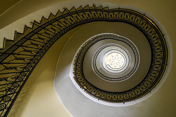 istock Elegant spiral staircase with ornate iron railing and skylight 2215938388