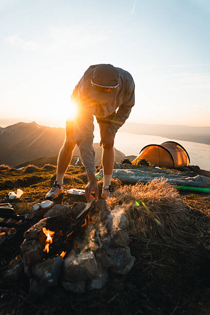 istock Young man prepares meal campsite on mountain peak 2215939172