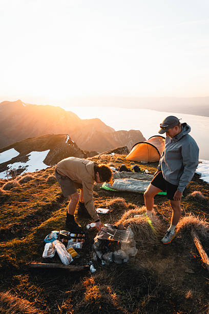 istock Young men prepare meal at campsite on mountain peak 2215939196