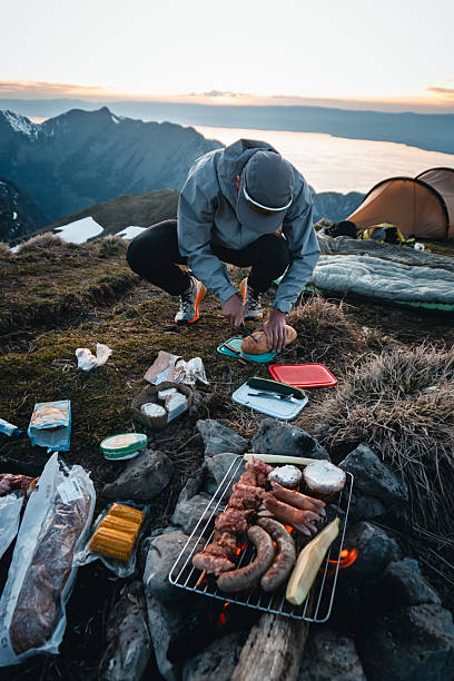 istock Young man prepares meal at campsite on mountain peak 2215939294