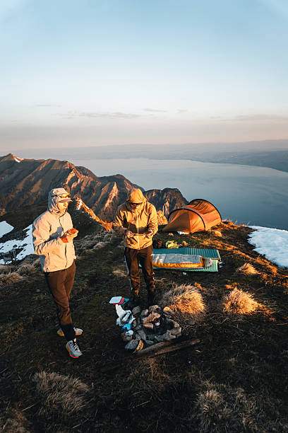 istock Young men prepare meal at campsite on mountain peak 2215939427