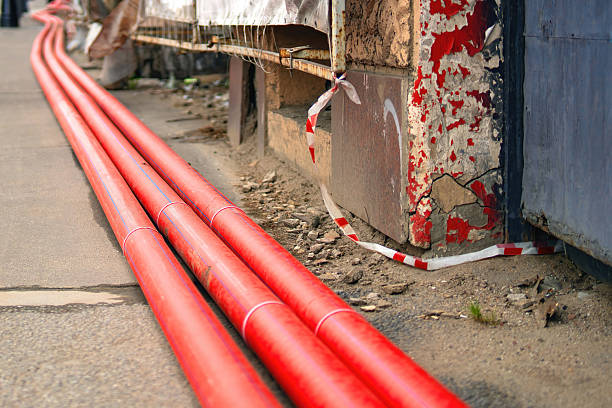 istock Three large red plastic sewer pipes installed near a building under renovation, showcasing urban infrastructure work 2215939579
