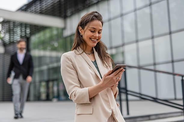 istock Businesswoman Checking Smartphone While Walking Outside Office 2215940117