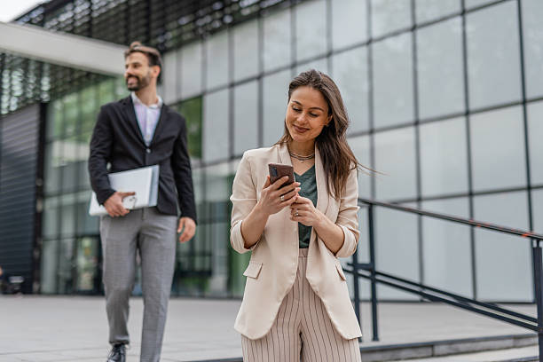 istock Businesswoman Checking Smartphone While Walking Outside Office 2215940120