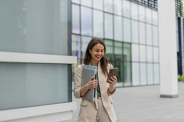 istock Young Entrepreneur Engaging with Phone While Holding Laptop 2215940302