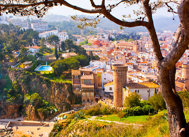 Defensive medieval wall and tower, townscape in the background . Tossa de Mar, Costa Brava, Girona, Catalunya, Spain
