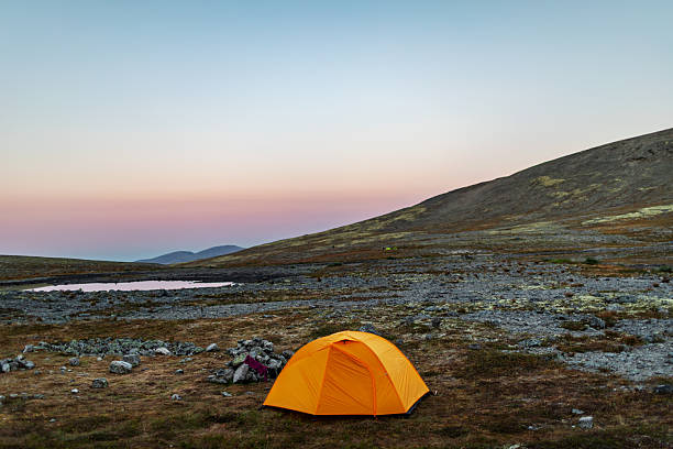 Tent near mountain lake at camping in twilight