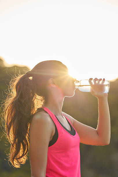 istock Woman drinks water during sunset while exercising outdoors in a vibrant pink tank top 2215943190