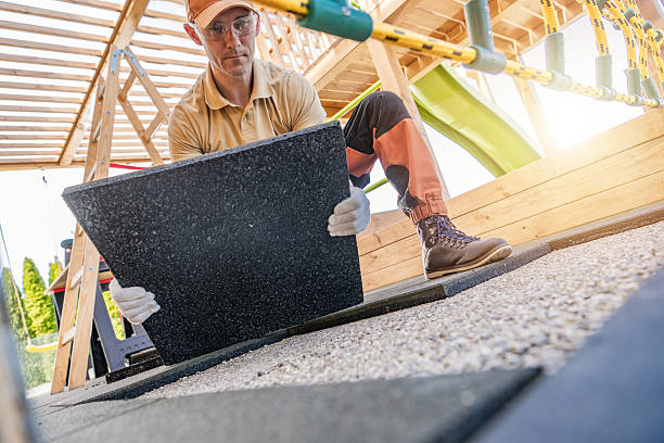 istock Worker Laying Down Rubber Tiles in a Playground Renovation Project During a Sunny Afternoon in a Suburban Area 2215947850